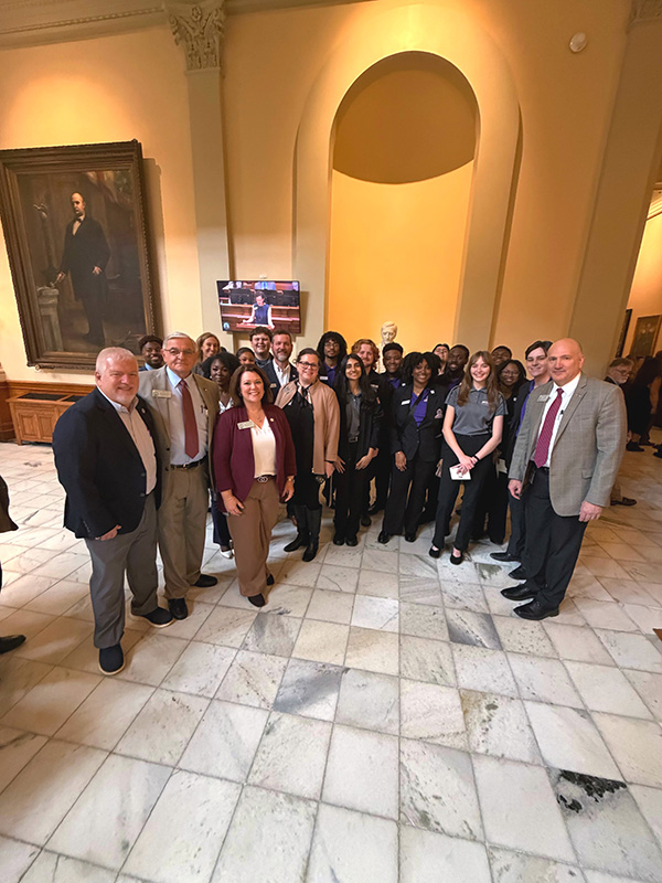 President's Torch Society students and state officials gather for a group photo in the Capitol’s grand hallway.